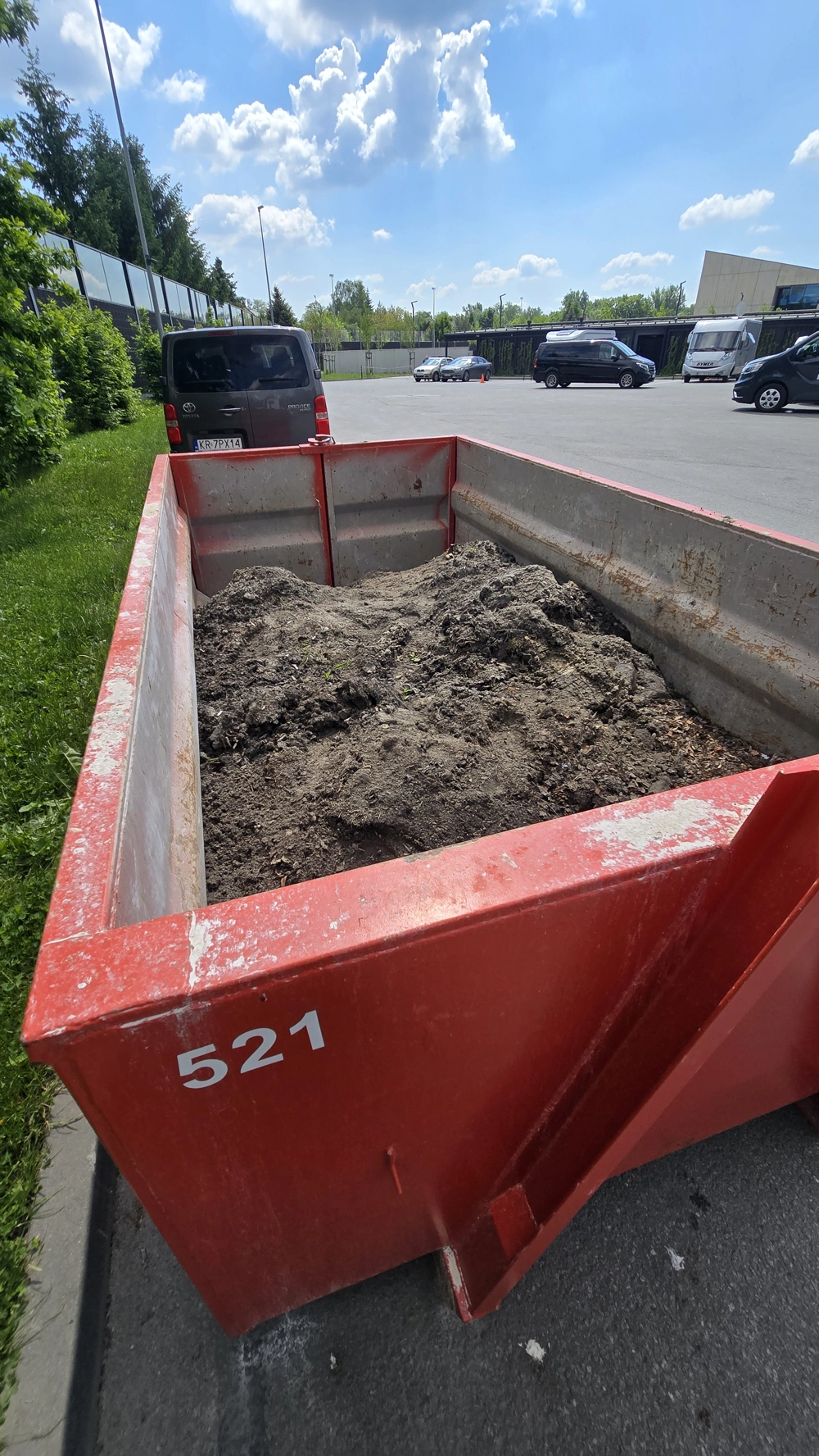 Czerwony kontener częściowo wypełniony ziemią na parkingu – Wywóz ziemi
