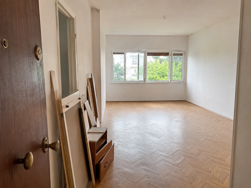 Puste mieszkanie po remoncie z drewnianym parkietem i deskami przy drzwiach, wywóz odpadów budowlanych