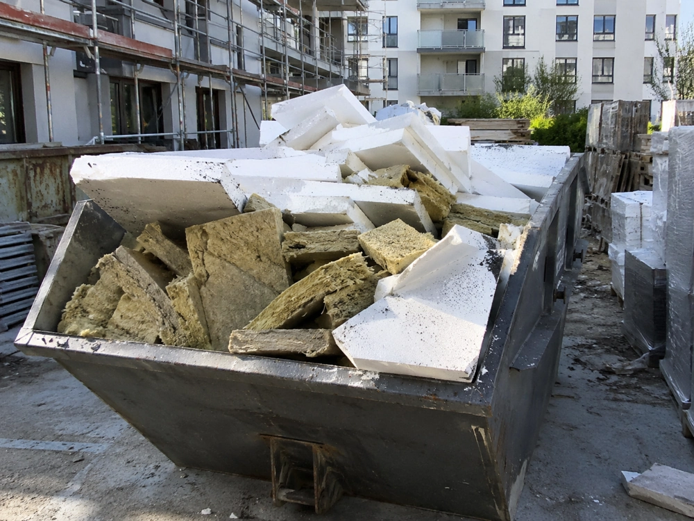 Kontener wynajęty na wywóz odpadów budowlanych wypełniony styropianem i wełną mineralną